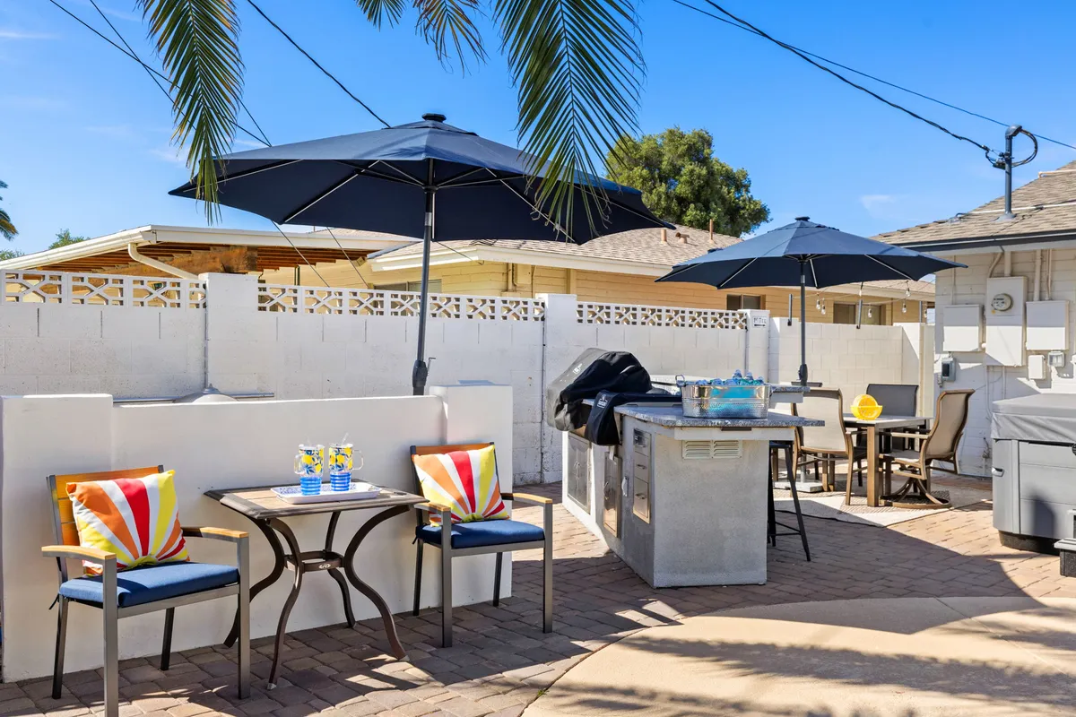 A vibrant outdoor dining and barbecue area complete with a grill, colorful cushions, parasol umbrellas, and ample seating. This festive setup is ideal for team lunches or group celebrations under the Arizona sun.