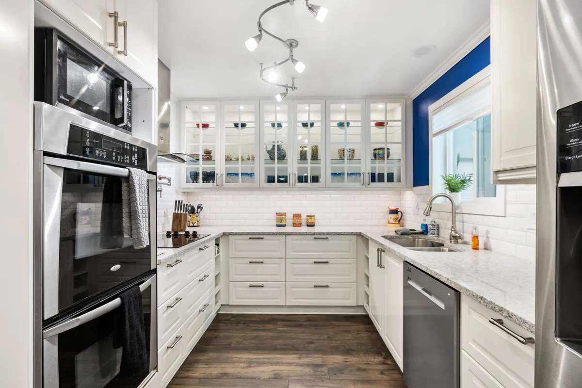 A modern kitchen featuring stainless steel appliances, granite countertops, and open shelving adorned with colorful jars. The scene exudes a welcoming atmosphere, perfect for cooking, baking, or entertaining guests, with ample counter space for meal preparation.