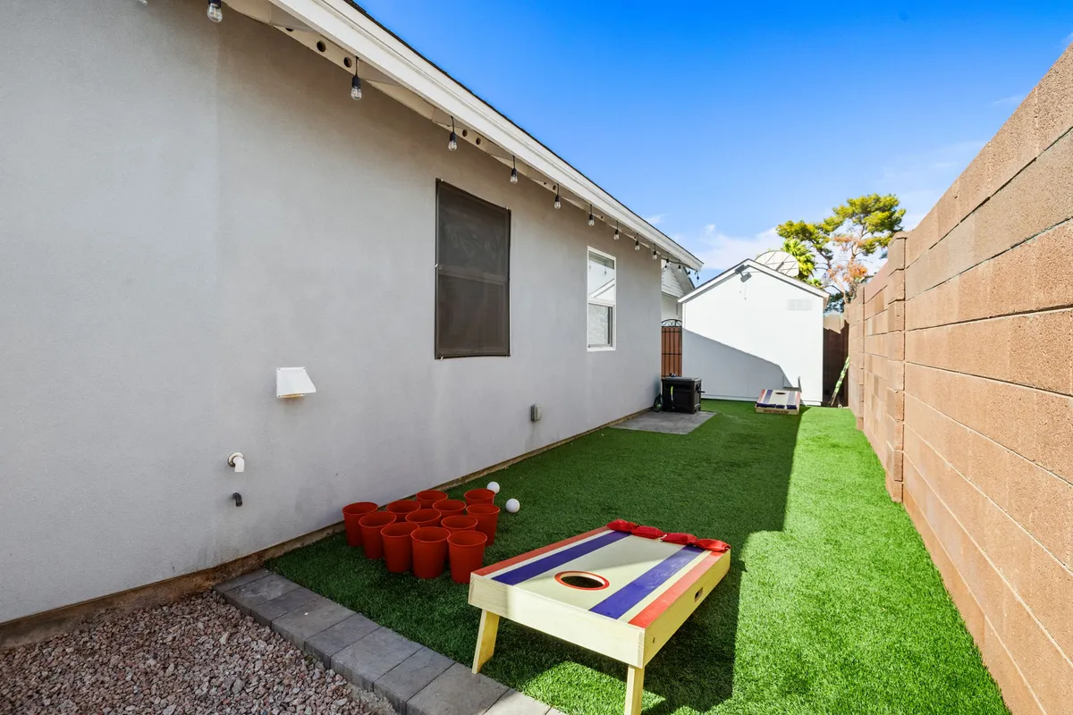 This vibrant exterior scene features a cornhole game set on a lawn area, with planters adding greenery. The area invites families and groups to engage in playful outdoor activities and gatherings, complementing the theme of fun and adventure.