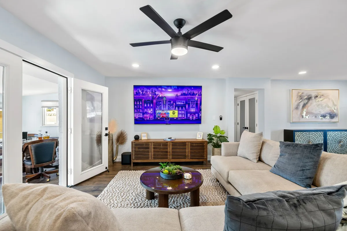 A comfortable modern sofa, coffee table, and a large TV set the scene for relaxation and entertainment. Bright artwork adds a cheerful touch, creating a space ideal for movie nights or group hangouts.